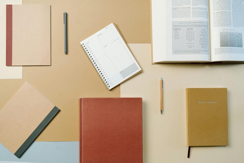 Flat Lay of Books and Notebooks on Brown Background